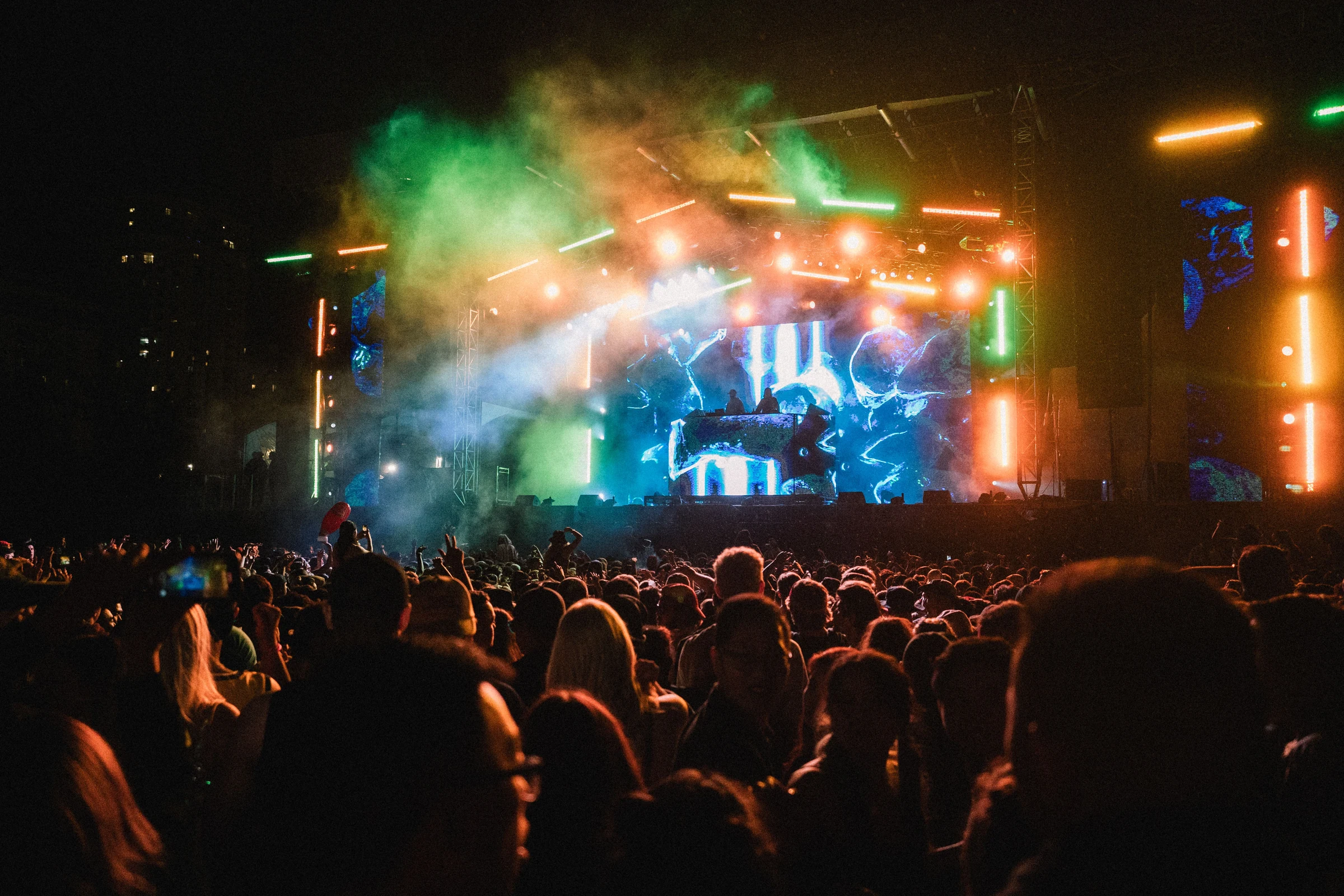 Crowd facing a concert stage with animated visuals across large LED screens